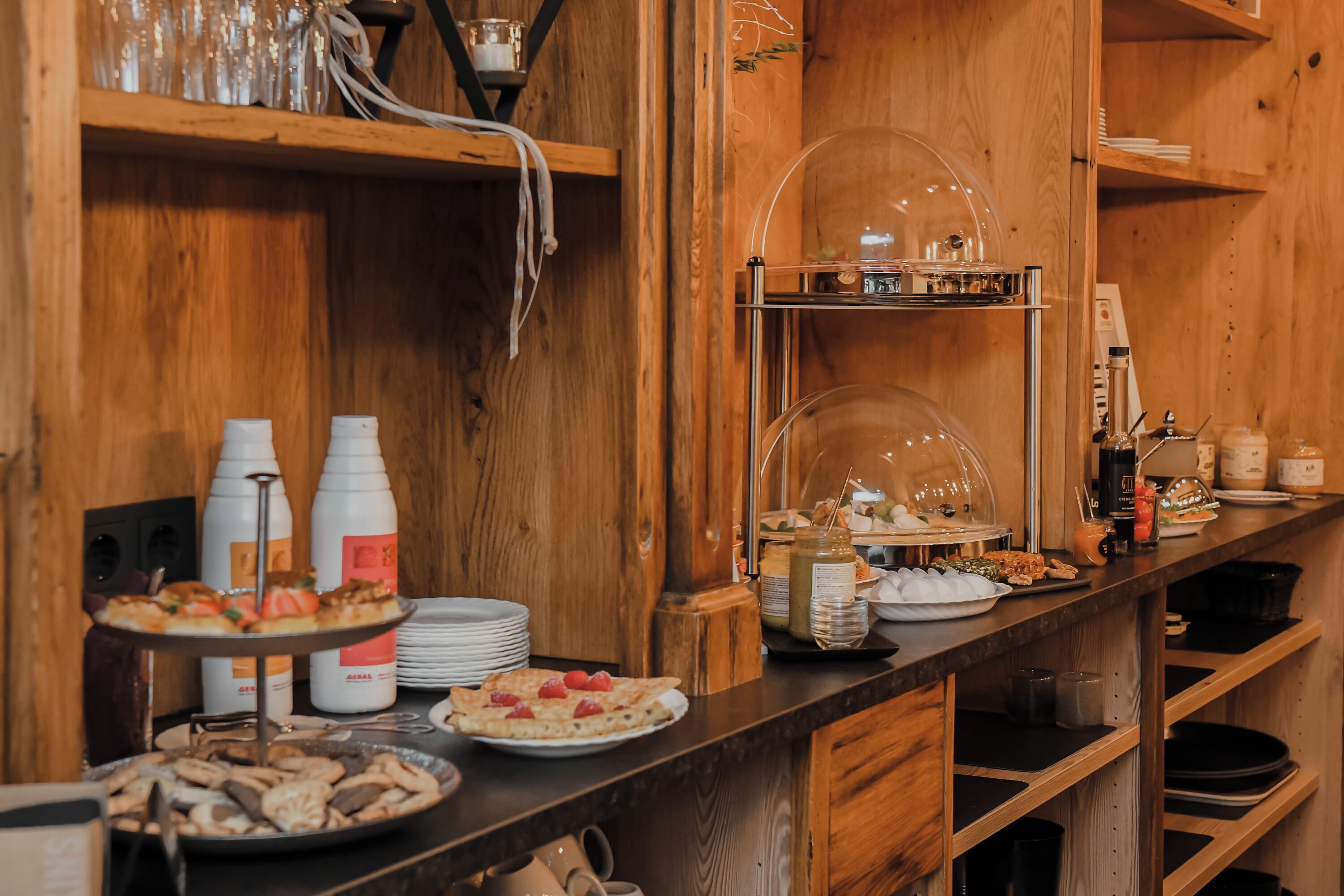 A buffet setup with various food items, including a pizza, pastries, and condiments.