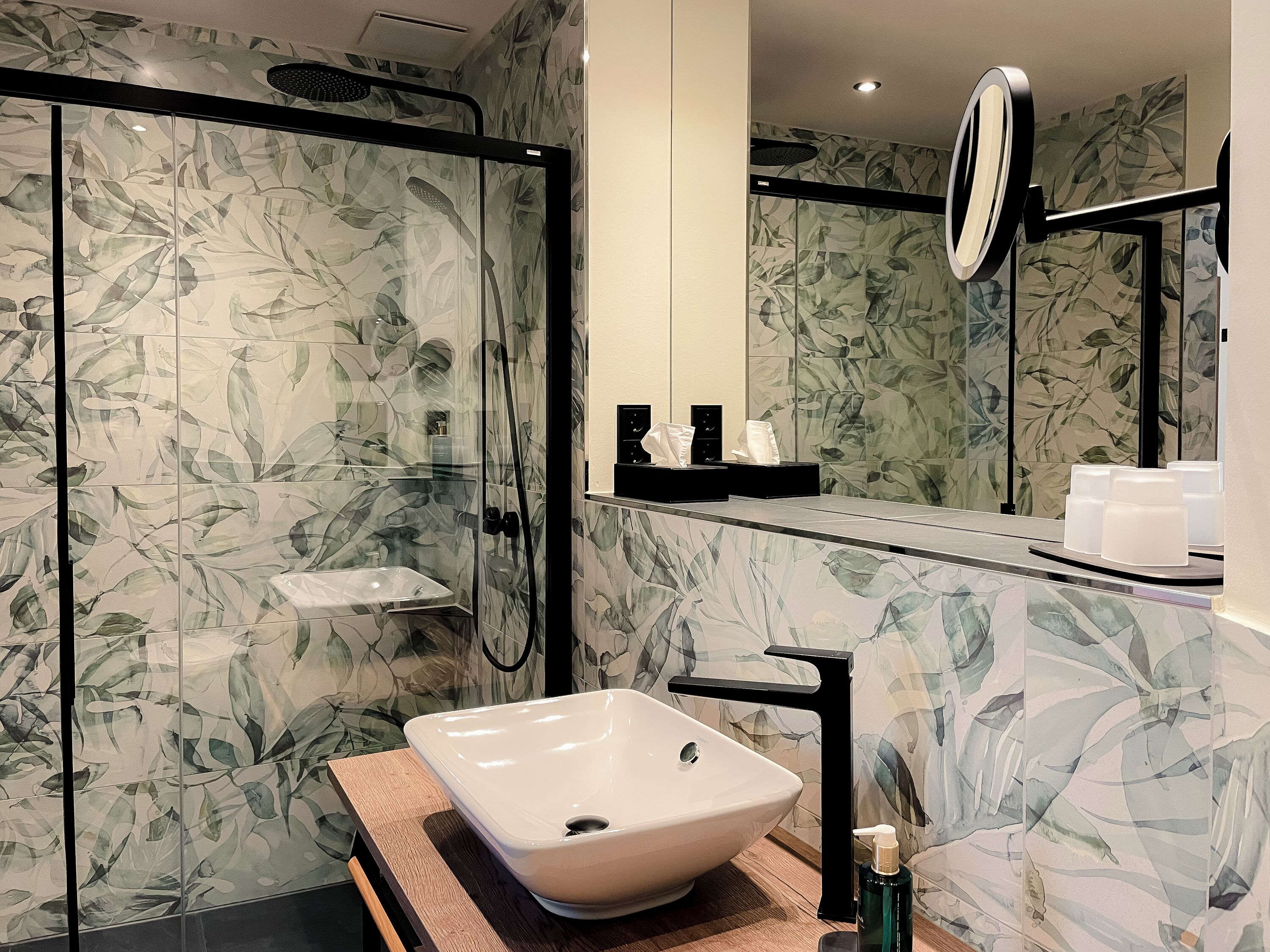 Ein modernes Badezimmer mit einer Duschkabine aus Glas, einem weißen Waschbecken und einem Spiegel darüber.