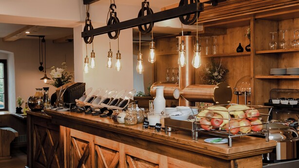 A wooden counter with a rustic design, featuring a coffee machine, a fruit display, and hanging light fixtures. - Altstadt-Hotel (Freiberg)