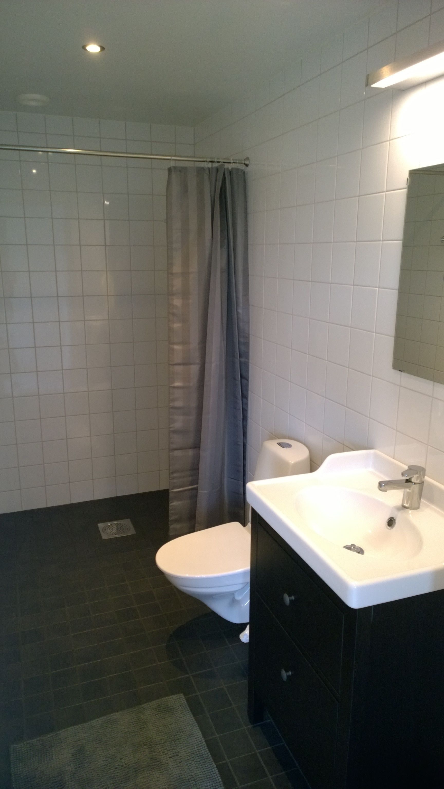 Un baño con inodoro blanco, lavamanos con espejo y cortina de ducha.