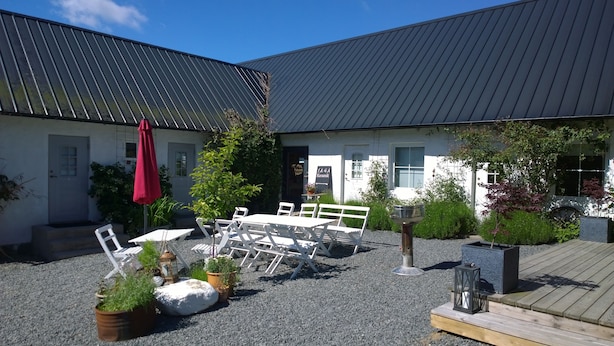 A courtyard with outdoor seating, a building with a metal roof, and a sign that reads "JASA Keramik". - Elisetorp (Kivik)