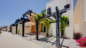 A covered outdoor area with a pergola, stone flooring, and a building with a green door and white walls. - ‘Casa Verde’ in Cabo San Lucas -  3 Mi to Marina! (Cabo San Lucas)