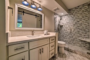 Une salle de bain moderne avec un grand miroir, un lavabo et un espace douche.