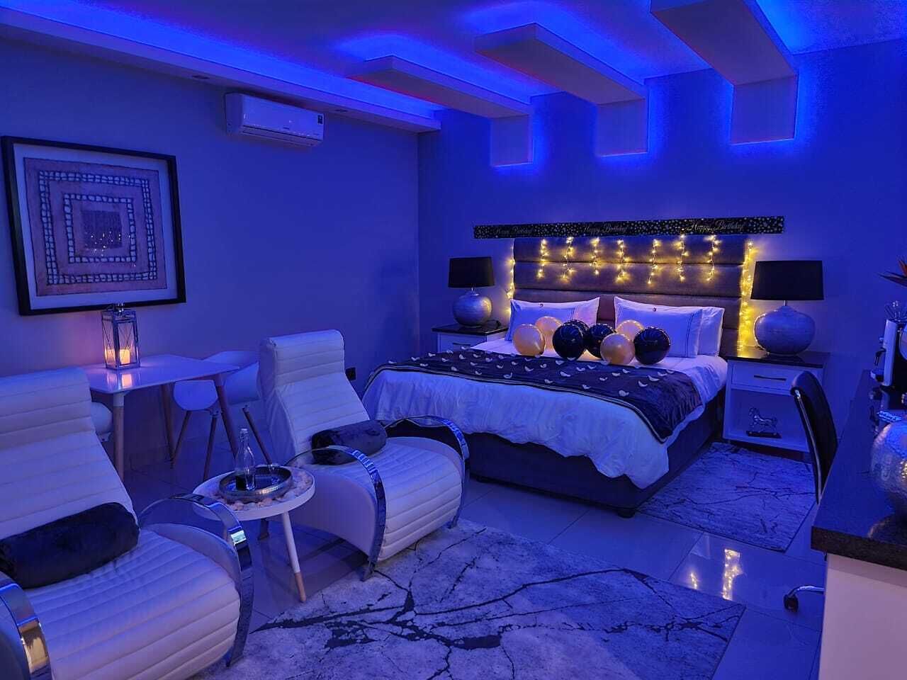 A modern bedroom with a bed, two chairs, a small table, and a nightstand.