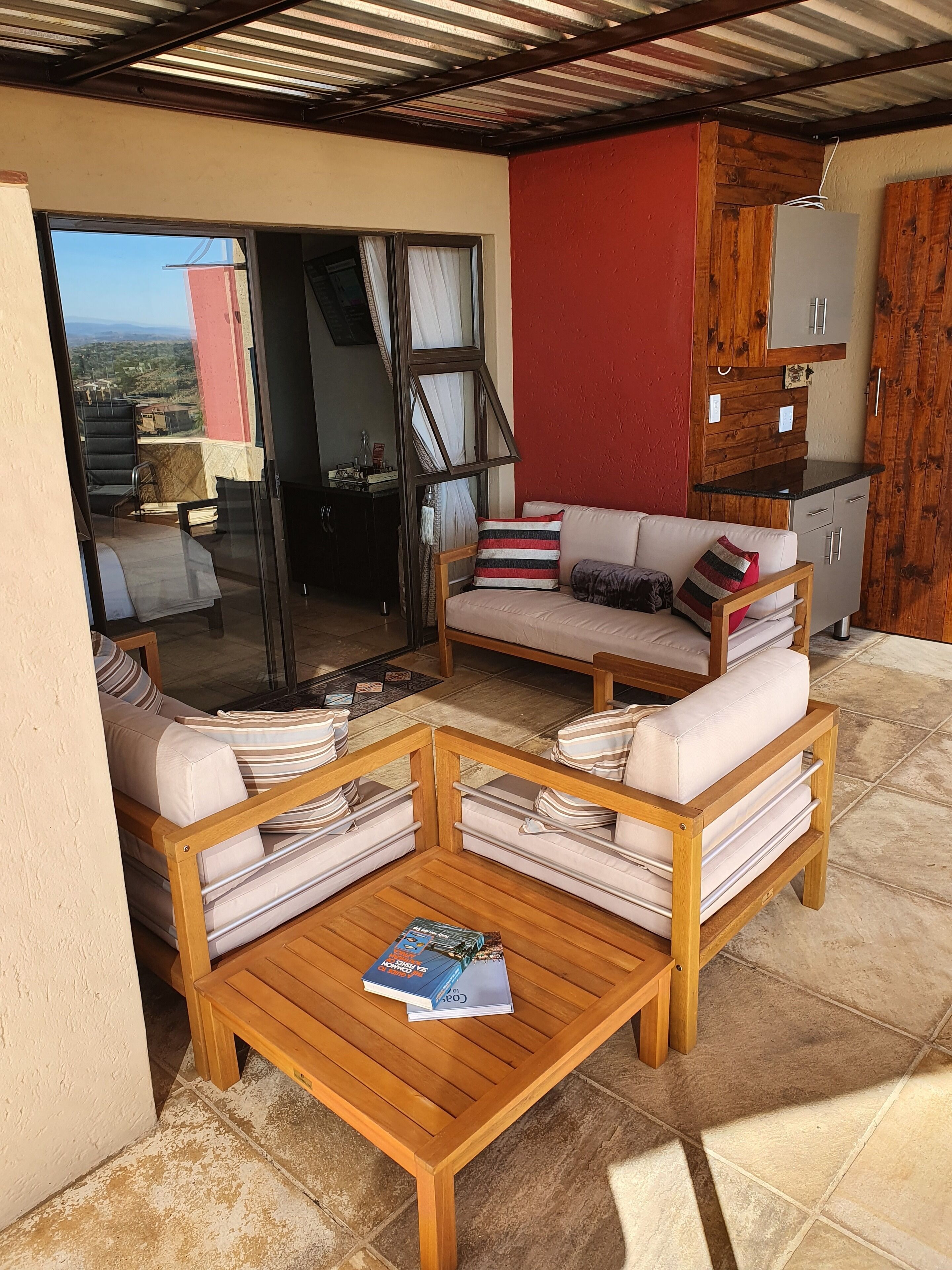 Un área de estar exterior acogedora con dos sofás y una mesa de centro, una puerta corrediza de vidrio que da a un balcón y un mueble de madera.