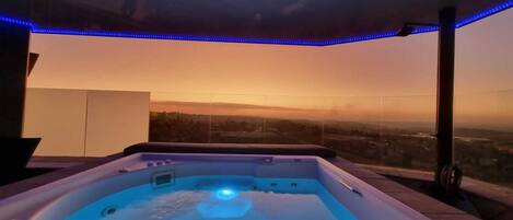 A hot tub with a view of a sunset over a cityscape.