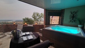 Een balkon met een jacuzzi, een tafel met stoelen en uitzicht op de stad.
