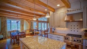 A spacious kitchen with granite countertops, wooden beams, and white cabinetry. - Elegant Mountain Dream Escape: 3BR with Fireplace & Views (Mill Spring)