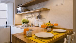 Une table en bois, des assiettes, des tasses et un panier de fruits : tout est prêt pour le petit-déjeuner.