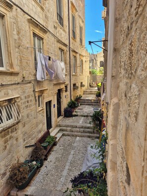 A narrow alley with stone buildings, a clothesline with garments, and potted plants. - Luxury Apartment Lina - I (Dubrovnik)