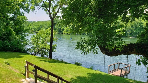 A wooden staircase leading down to a dock by a lake, surrounded by lush greenery. - 'Riverside Hide-A-Way' w/ Fire Pit, Fishing, BBQ (Mountain Home)