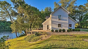 A two-story house with a dock, surrounded by lush greenery and a lake. - 'Riverside Hide-A-Way' w/ Fire Pit, Fishing, BBQ (Mountain Home)