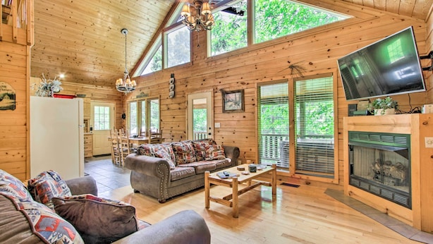 A spacious wooden cabin with a living room featuring a sofa, a coffee table, and a fireplace. - Cabin w/ Hot Tub & Deck ~ 7 Mi to Pigeon Forge! (Sevierville)