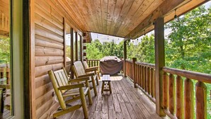 A wooden deck with rocking chairs and a barbecue grill. - Cabin w/ Hot Tub & Deck ~ 7 Mi to Pigeon Forge! (Sevierville)