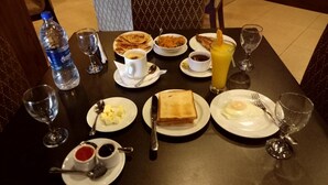 A breakfast table with plates of toast, eggs, and pancakes, along with beverages and condiments. - The Alina Hotel & Suites (Chittagong)