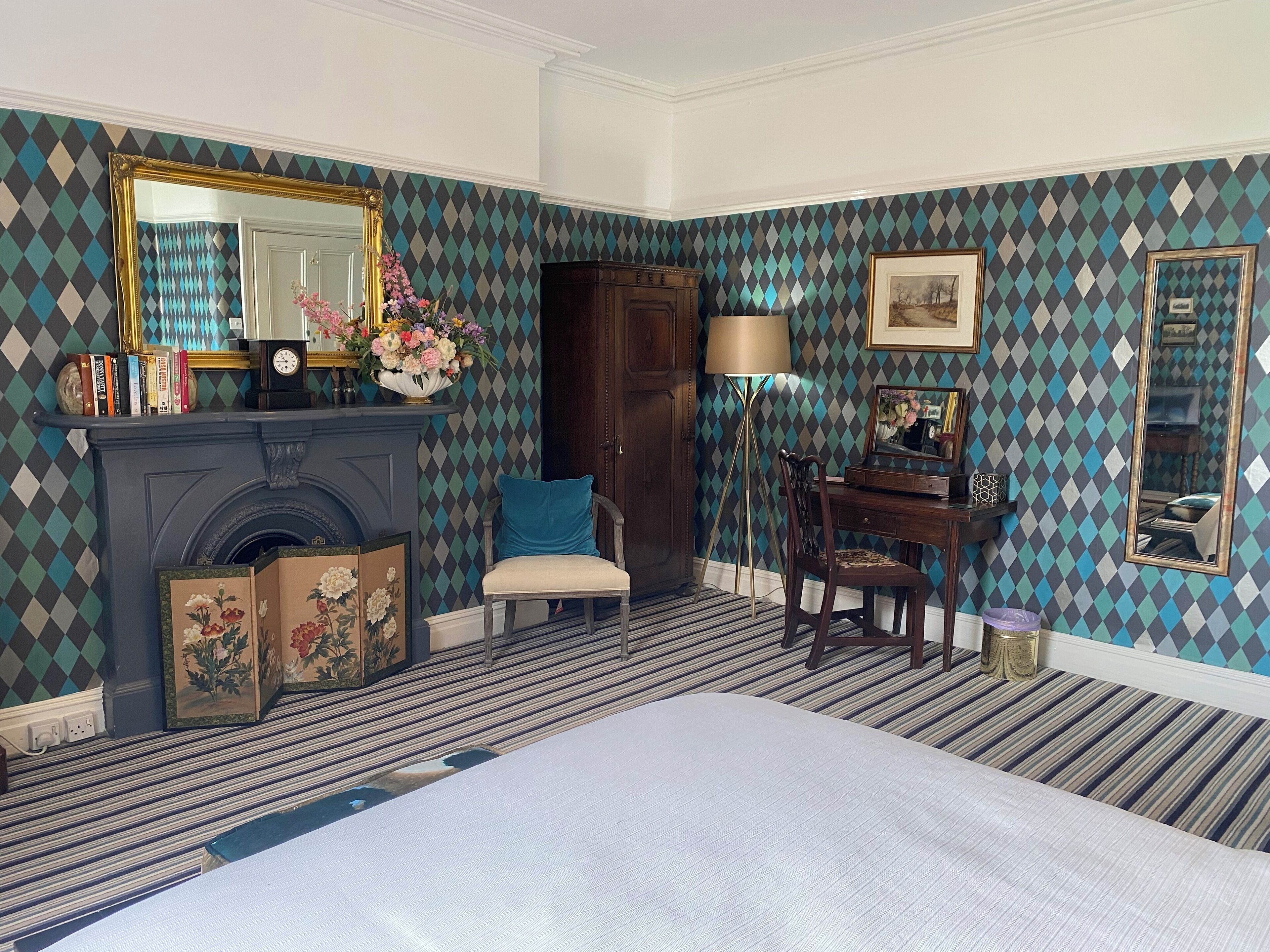 A room with a fireplace, a bed, a desk, and a chair.