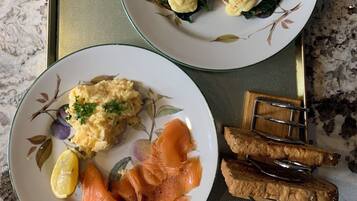 Ett bricka med två tallrikar mat, inklusive ägg Benedict och rökt lax, placerad på en bänkskiva av granit.