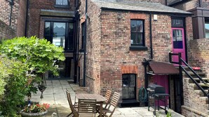 A brick building with a patio area featuring outdoor furniture and potted plants. - Aberley House (Liverpool)
