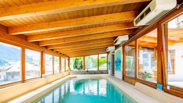 Una piscina interna con travi in legno e ampie finestre.