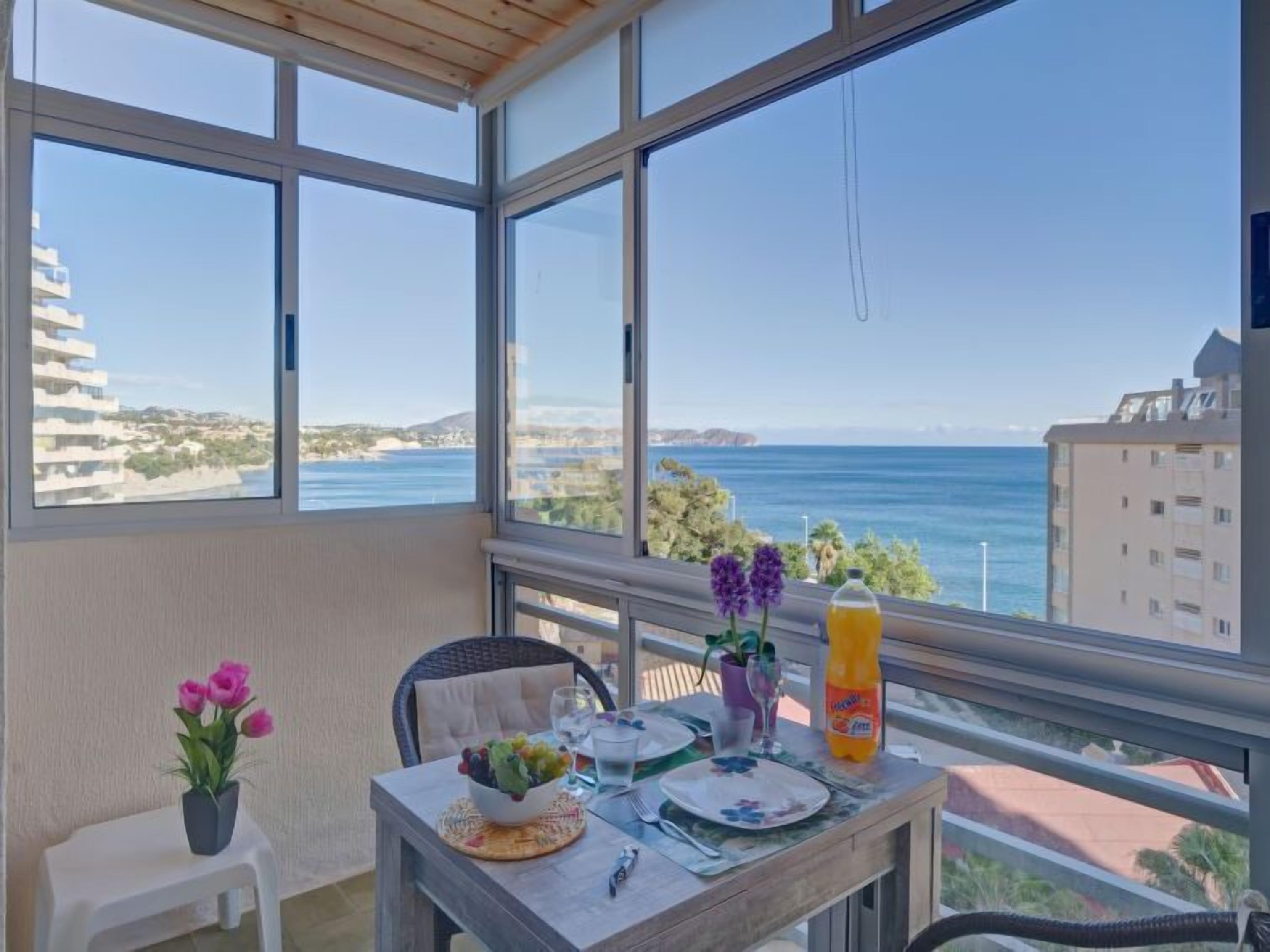 Een balkon met een gedekte tafel, met uitzicht op de kust.