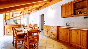 Eine geräumige Küche mit Holzschränken, einem Essbereich mit Stühlen und einem gefliesten Boden.