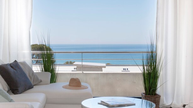 Un balcón con un sofá blanco, una mesa redonda y vista al mar.