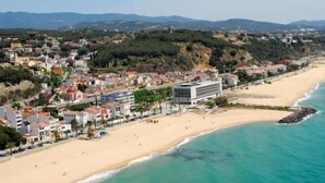 Un pueblo costero con playa, edificios y un paisaje montañoso al fondo.
