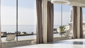 Una habitación amplia con ventanas grandes, vistas al mar y una lámpara de techo moderna.