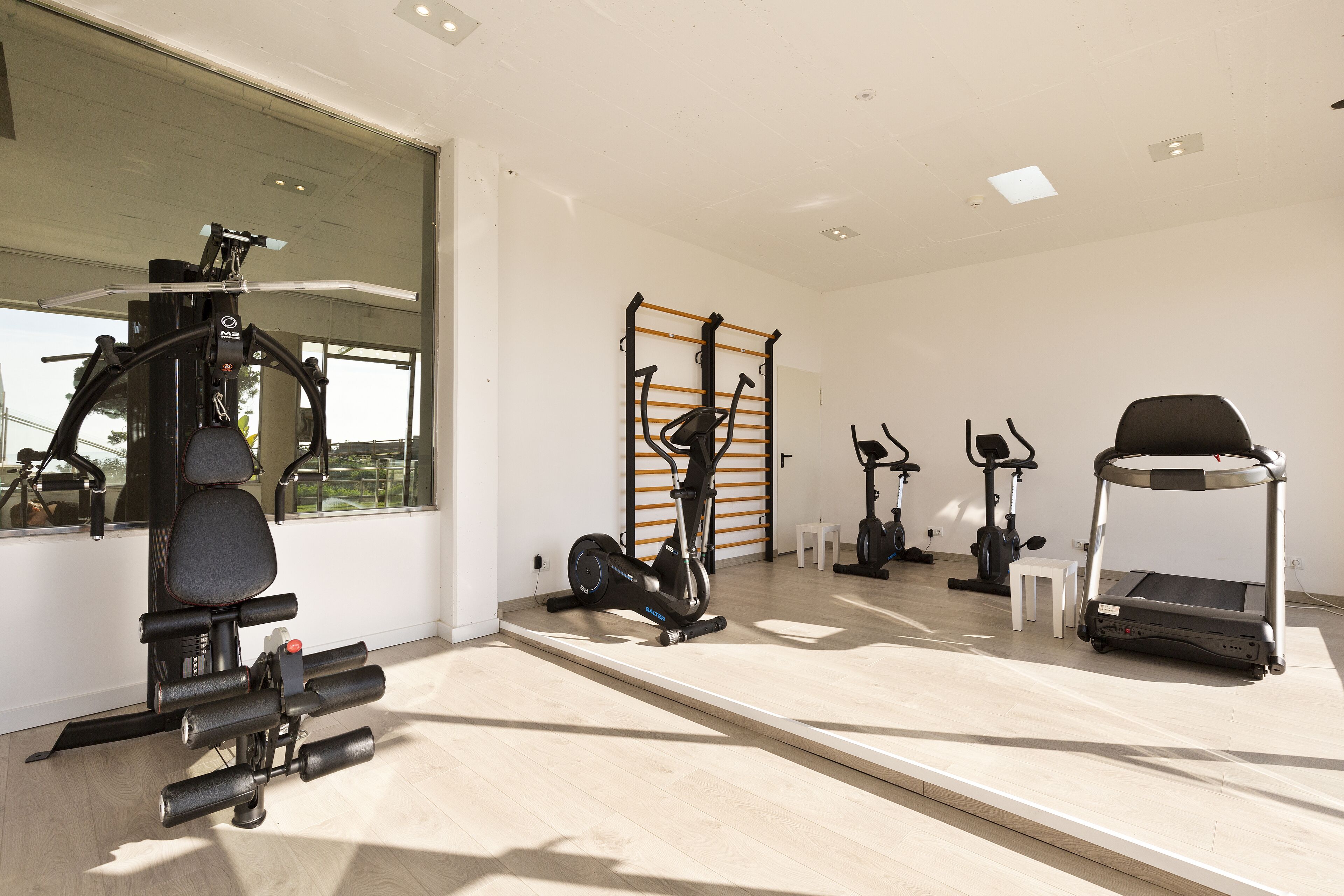 Een moderne sportschool met diverse fitnessapparaten, waaronder een elliptische trainer, een hometrainer en een loopband.