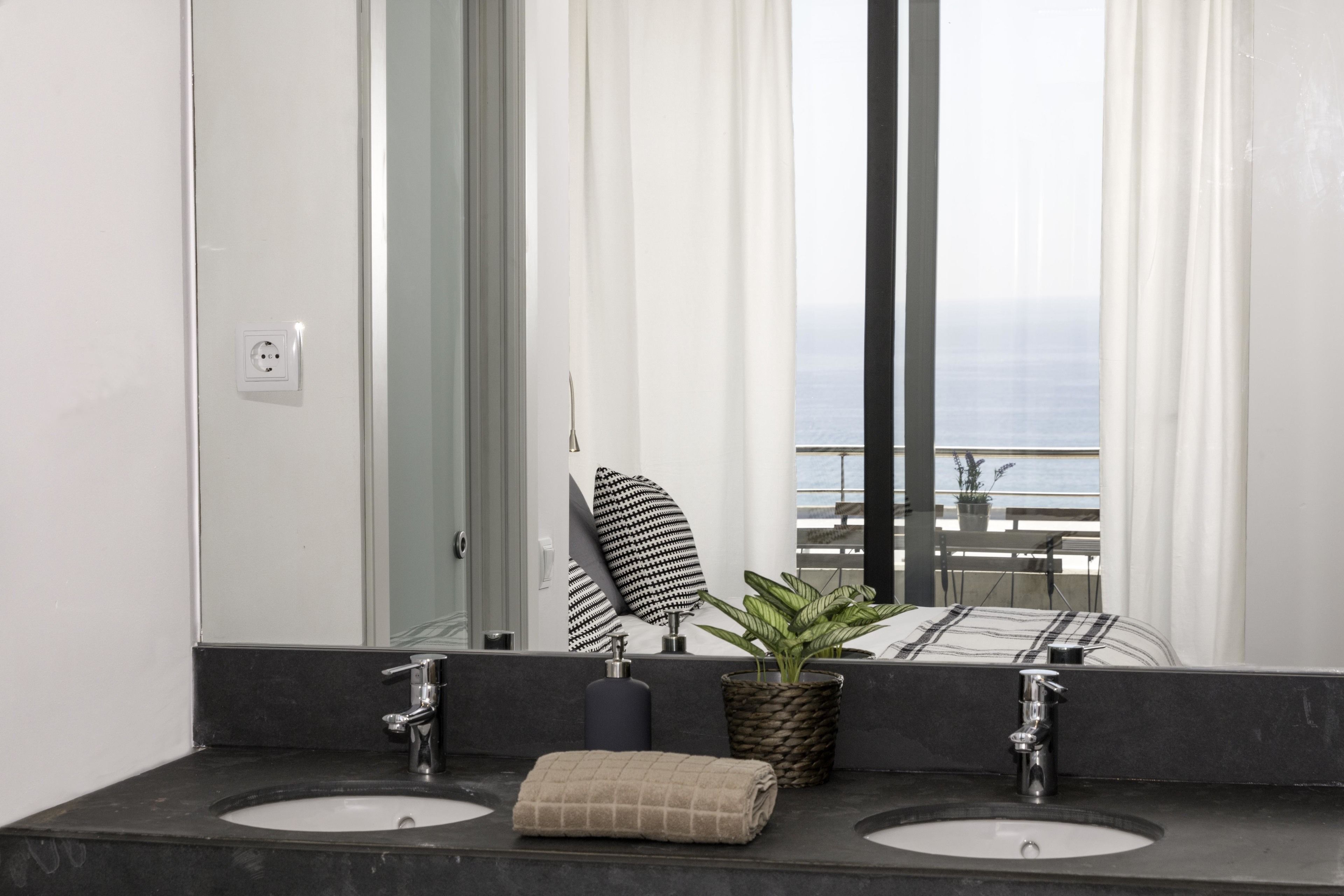 Une salle de bain avec deux lavabos, un miroir, une serviette et une plante.