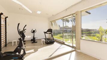 A spacious room with a large window, a treadmill, an elliptical, and a stationary bike.