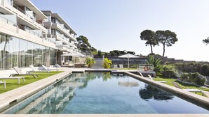 Un hotel moderno con piscina, zona de estar al aire libre y vistas del paisaje circundante.