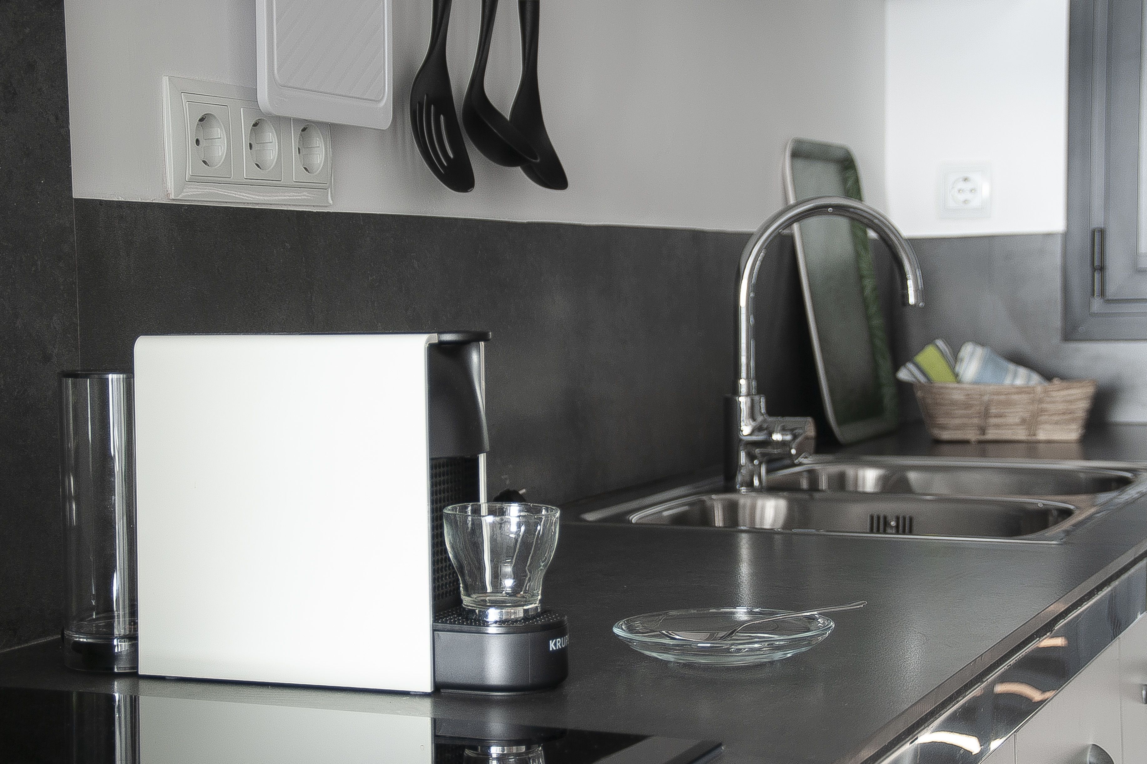 Une cuisine moderne équipée d’une cuisinière intégrée, d’un évier et d’un récipient en verre posé sur le plan de travail.