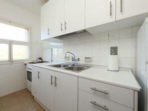 Een koelkast, een oven, kookgerei, borden en bestek