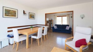 Un comedor con una mesa y sillas de madera, un sofá azul y un sillón blanco.