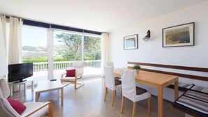 Una habitación moderna con balcón, una mesa de comedor, sillas, televisor y obras de arte en la pared.