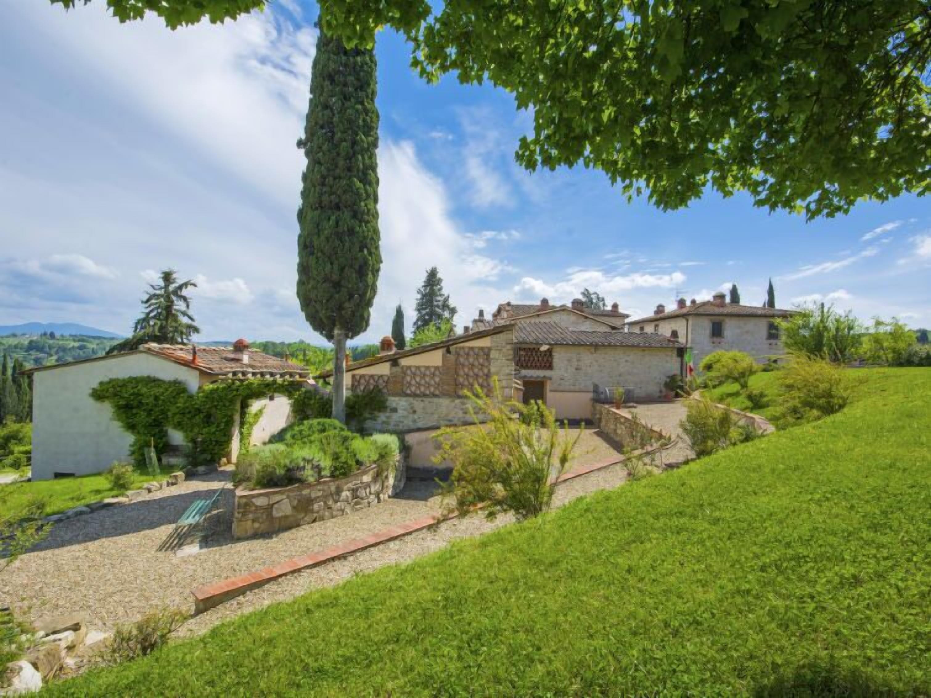 Una casa in pietra tradizionale con tetto in tegole, immersa nel verde e sotto un cielo sereno.