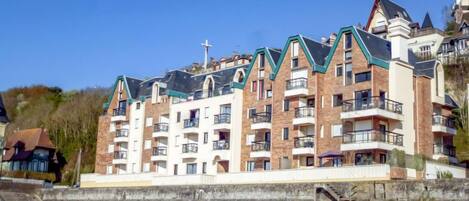 A multi-story hotel with a modern architectural design, featuring balconies and a prominent cross on the roof.