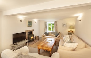 A living room with a fireplace, sofas, a coffee table, and a television.