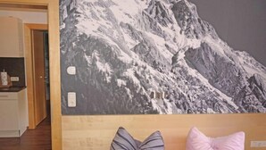 Ein Schlafzimmer mit einem Bett, Kissen und einem Wandbild einer Berglandschaft.