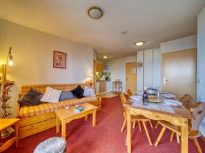 A cozy living room with a sofa, coffee table, and dining table set for four.
