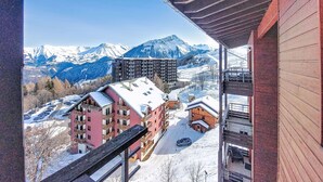 A view of a mountain resort with snow-covered buildings and a clear sky. - Bâtiment A by Interhome (Le Corbier)