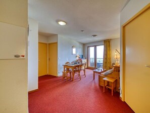 A hotel room with a dining area, a sofa, and a window with curtains.