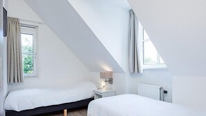 A modern, well-lit bedroom with two beds, a nightstand, and a window with curtains. - Vacation home Alk 8 by Interhome (Noordwijk)
