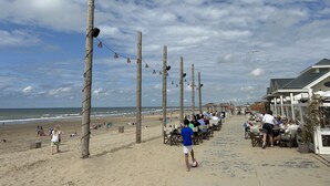 A beachside restaurant with outdoor seating, wooden poles, and a view of the ocean. - Vacation home Alk 8 by Interhome (Noordwijk)