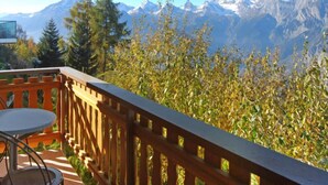 A balcony with a view of snow-capped mountains, a wooden railing, and a table with chairs. - Vacation home Lara by Interhome (Nendaz)
