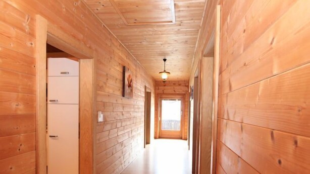 A wooden interior hallway with a ceiling fan, a refrigerator, and a door leading to another room. - Apartment Heidi by Interhome (Kaltenbach)