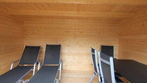A wooden cabin with four reclining chairs and a long table. - Apartment Heidi by Interhome (Kaltenbach)