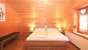 A cozy wooden cabin bedroom with a double bed, bedside lamps, and a bench. - Apartment Heidi by Interhome (Kaltenbach)