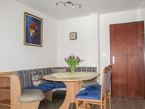 A room with a round wooden table, a blue cushioned bench, and a chair with blue cushions.